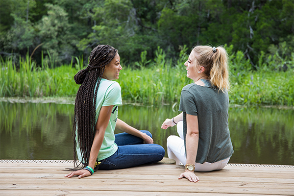Two UWF students sit on the dock on Thompson Bayou.