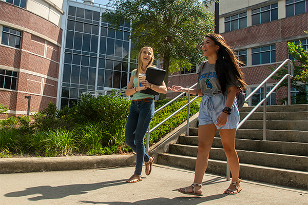 Two UWF students walk in front of the Hal Marcus College of Science and Engineering.